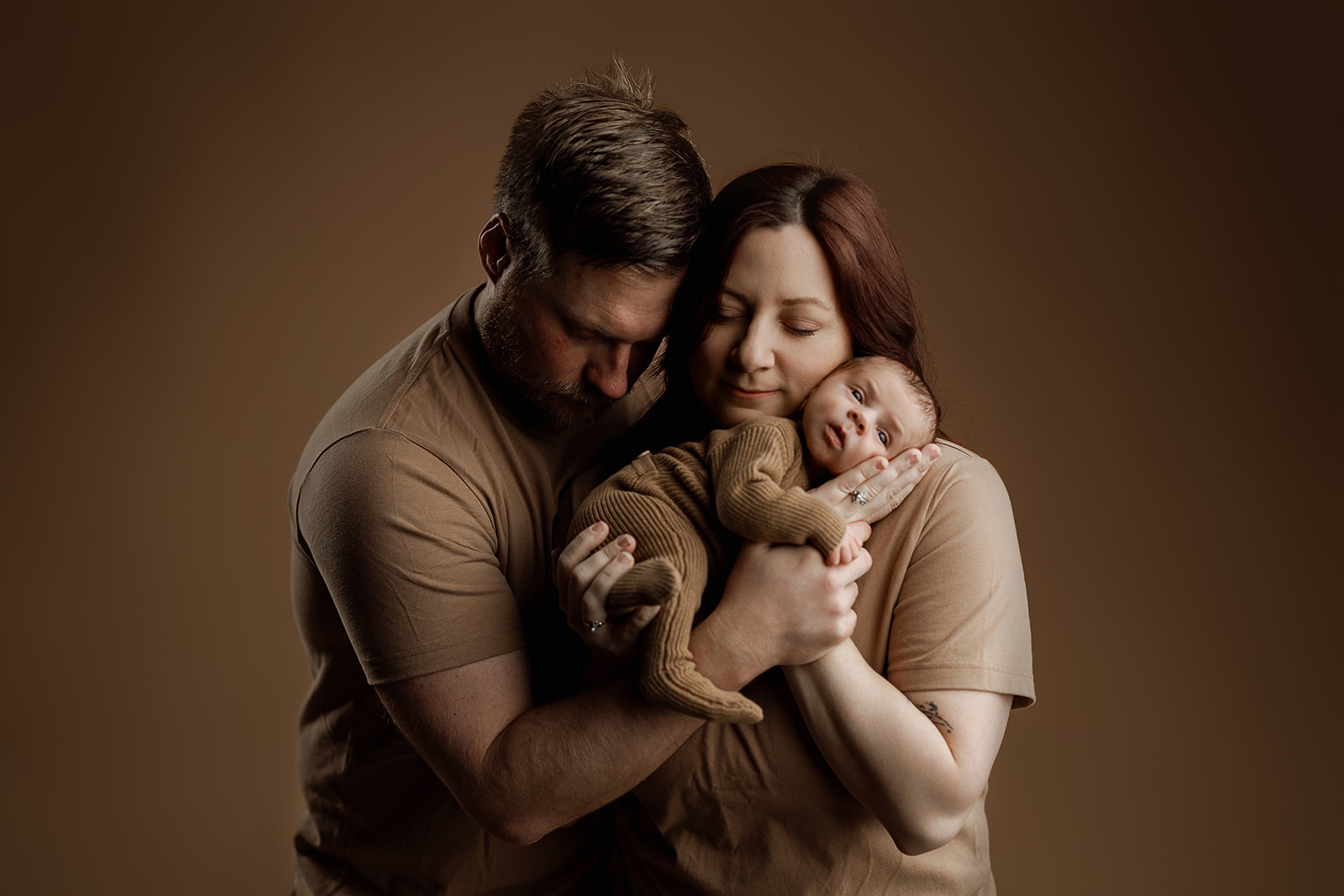 monochromatic newborn family photo with neutral clothing and seamless backdrop